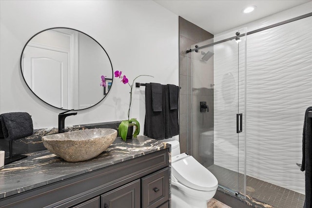 bathroom featuring toilet, vanity, and a shower with door