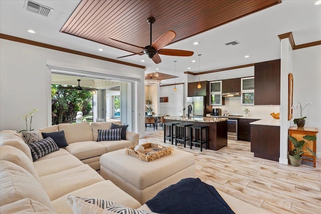 living room featuring ceiling fan, ornamental molding, light hardwood / wood-style flooring, and sink