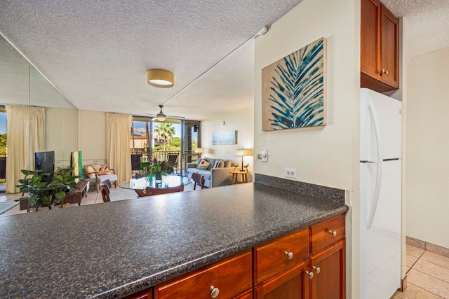 kitchen with ceiling fan, white refrigerator, light tile patterned flooring, and a textured ceiling