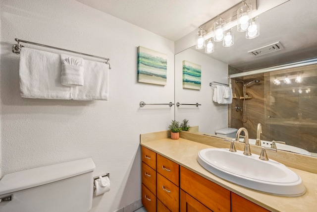 bathroom with vanity, toilet, a shower with door, and a textured ceiling