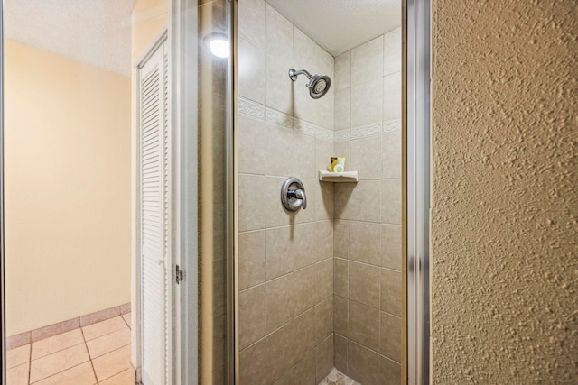 bathroom with tile patterned flooring, an enclosed shower, and a textured ceiling