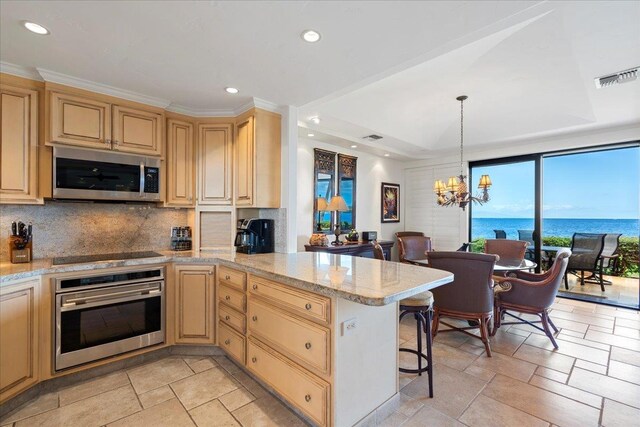 4850 Makena Alanui Rd Unit F-108, Kihei, HI 96753 - kitchen with a water view, decorative backsplash, appliances with stainless steel finishes, a peninsula, and a kitchen bar