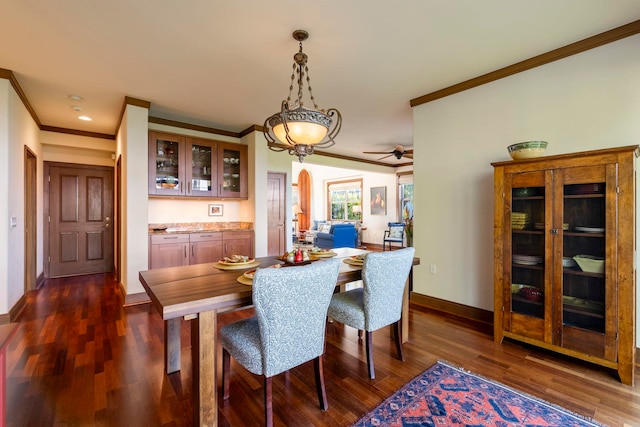 dining room with ceiling fan, ornamental molding, and dark wood-type flooring