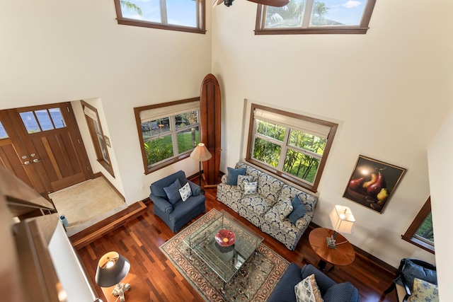 living room with ceiling fan, wood-type flooring, and a high ceiling