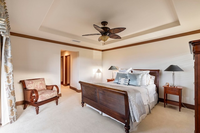 carpeted bedroom with a tray ceiling, ceiling fan, and crown molding