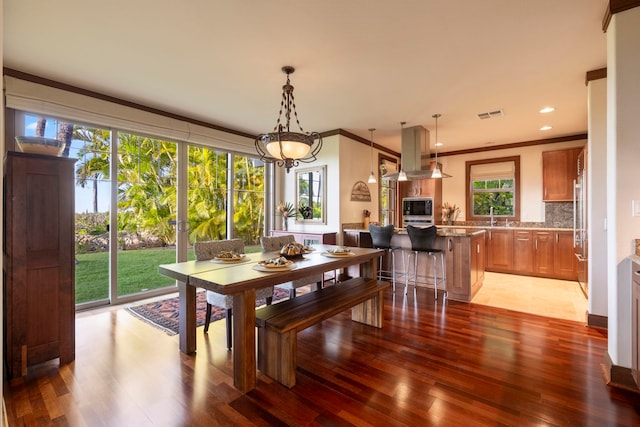 dining room featuring crown molding, sink, and hardwood / wood-style flooring