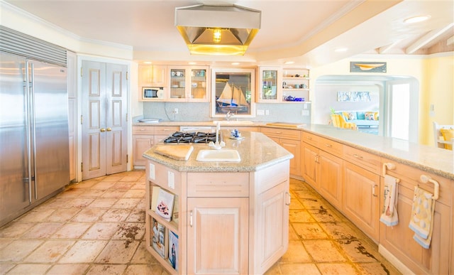 kitchen with built in appliances, tasteful backsplash, a tray ceiling, a kitchen island, and light brown cabinetry