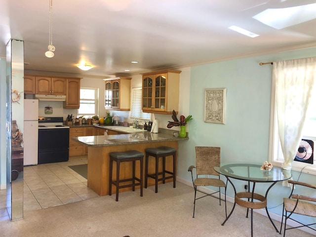 kitchen with a breakfast bar area, electric range oven, white refrigerator, light carpet, and kitchen peninsula