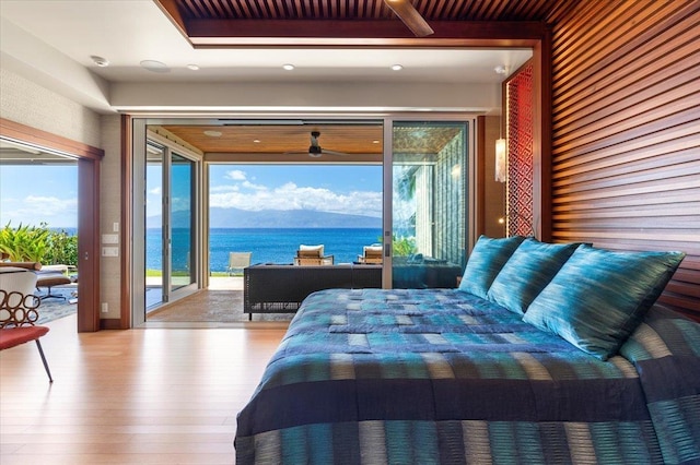 bedroom with light wood-type flooring, access to exterior, a water view, and multiple windows