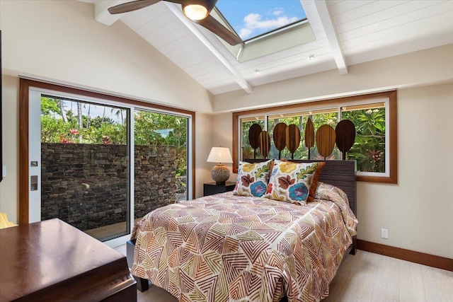 bedroom featuring ceiling fan, lofted ceiling with skylight, access to outside, and multiple windows