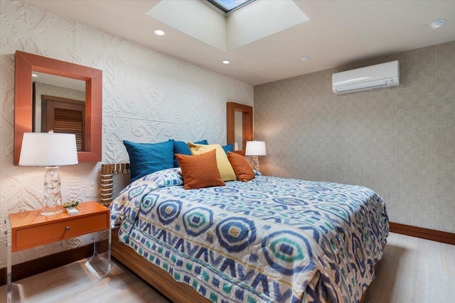 bedroom with a skylight, hardwood / wood-style floors, and a wall unit AC