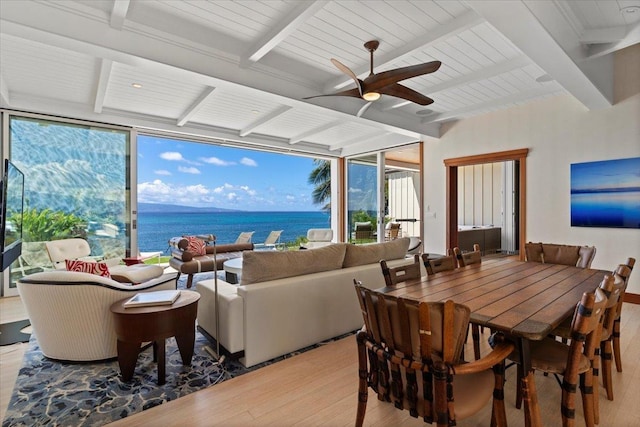 dining space featuring ceiling fan, light hardwood / wood-style flooring, beam ceiling, and a water view