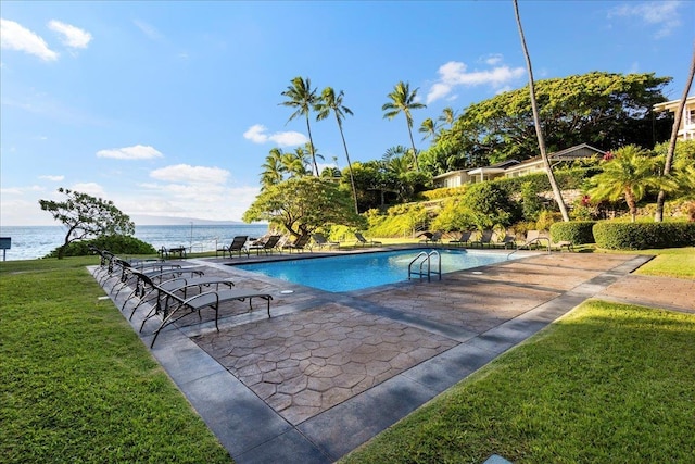 view of pool with a water view and a lawn