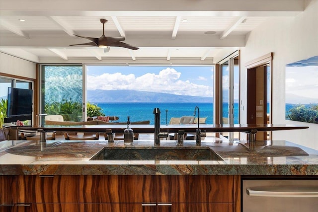 interior space featuring sink, dark stone countertops, beam ceiling, and a water and mountain view