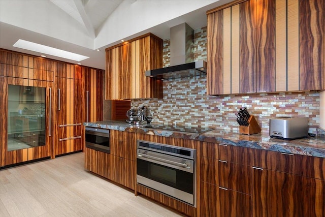 kitchen featuring wall chimney exhaust hood, tasteful backsplash, vaulted ceiling, and stainless steel appliances