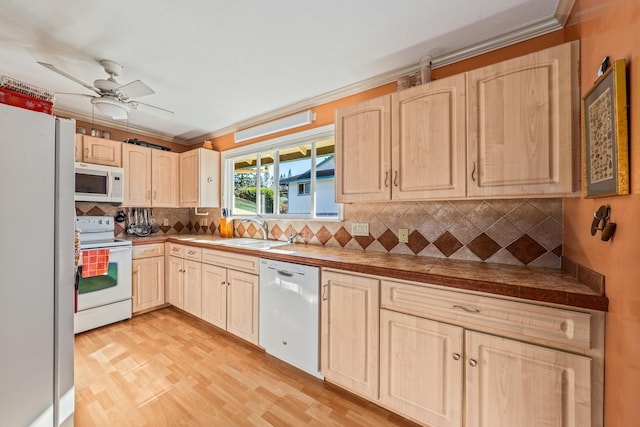 kitchen with light brown cabinetry, decorative backsplash, sink, and white appliances