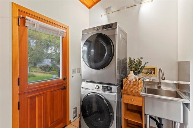 laundry area featuring sink, stacked washer / dryer, and light tile patterned floors