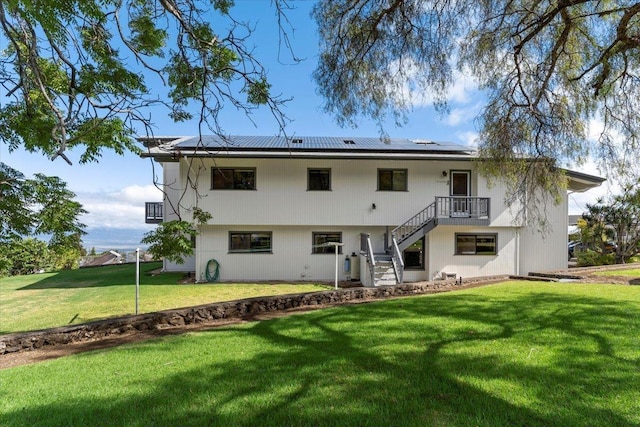 back of property with a lawn and solar panels