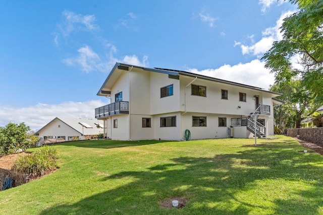 rear view of property with a balcony and a lawn