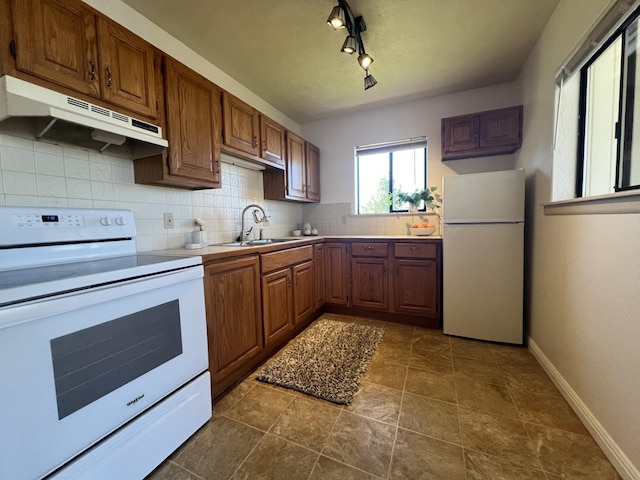 kitchen featuring dark tile patterned floors, sink, white appliances, and track lighting