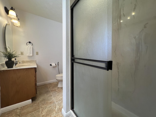 bathroom with an enclosed shower, vanity, toilet, and a textured ceiling