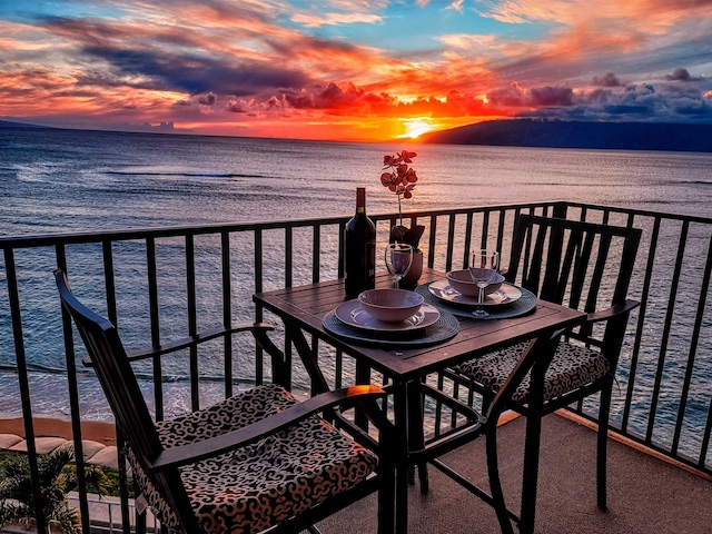 balcony at dusk featuring a water view