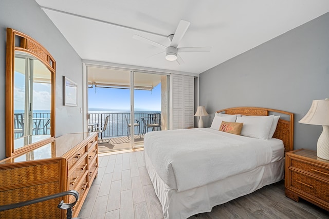 bedroom with access to exterior, wood finished floors, ceiling fan, and a wall of windows