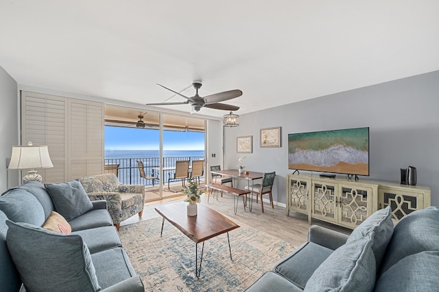 living area with ceiling fan, expansive windows, wood finished floors, and baseboards