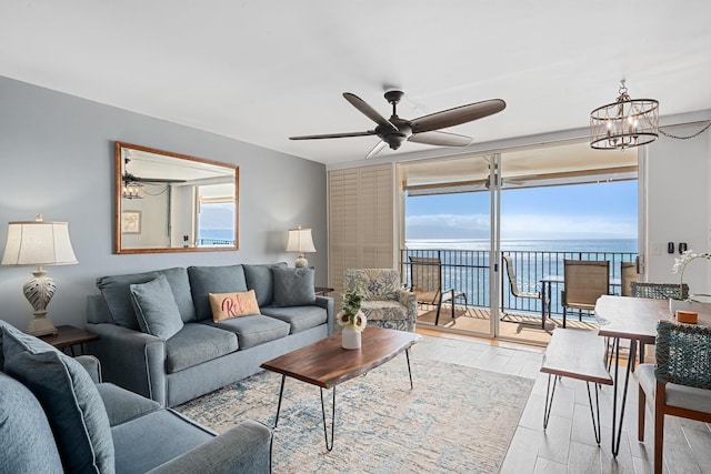 living area featuring a ceiling fan, a water view, and wood finished floors