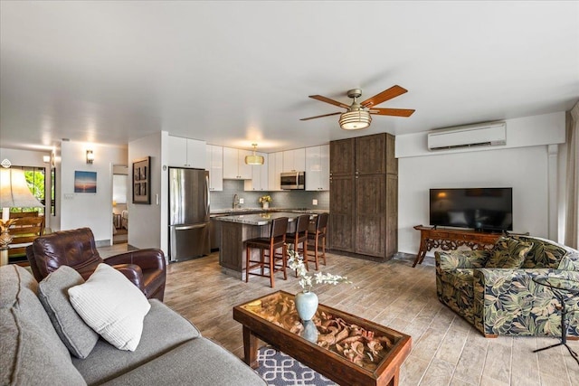 2387 S Kihei Rd Unit C108, Kihei, HI 96753 - living room featuring a wall unit AC, ceiling fan, and light wood-style flooring