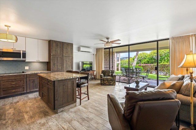 2387 S Kihei Rd Unit C108, Kihei, HI 96753 - kitchen featuring open floor plan, stainless steel microwave, a wall unit AC, a breakfast bar area, and white cabinets