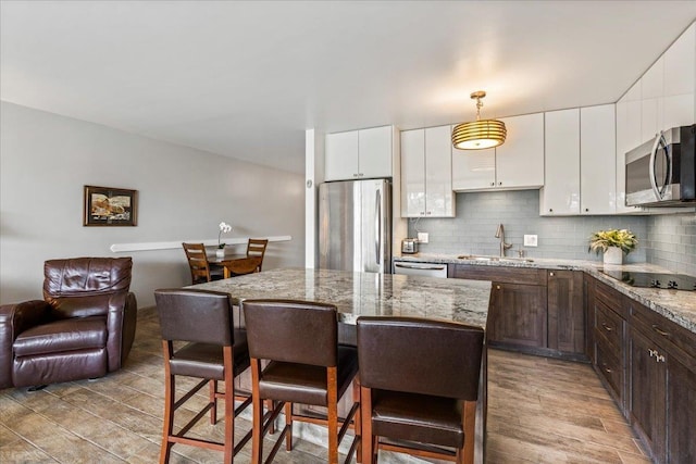 2387 S Kihei Rd Unit C108, Kihei, HI 96753 - kitchen with appliances with stainless steel finishes, a sink, dark brown cabinetry, a kitchen breakfast bar, and light wood-type flooring
