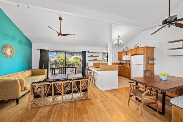 15 Kulanihakoi St Unit 3E, Kihei, HI 96753 - dining area featuring light wood-style flooring, ceiling fan with notable chandelier, and high vaulted ceiling