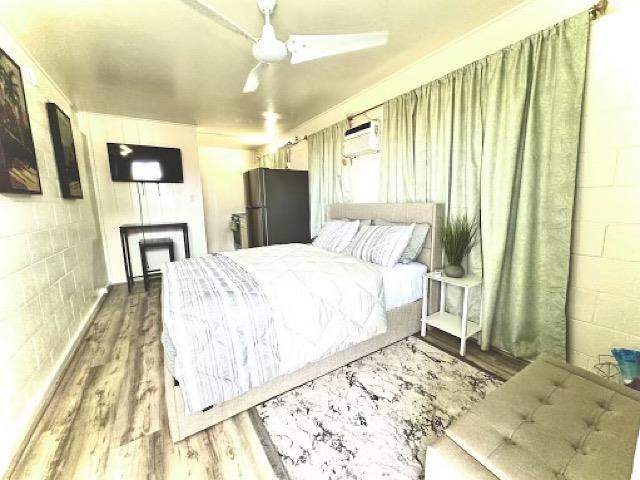 471 Liholiho St Unit 25, Wailuku, HI 96793 - bedroom featuring freestanding refrigerator, concrete block wall, and wood finished floors