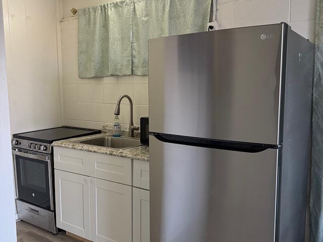 471 Liholiho St Unit 25, Wailuku, HI 96793 - kitchen with stainless steel appliances, white cabinets, wood finished floors, and light stone countertops