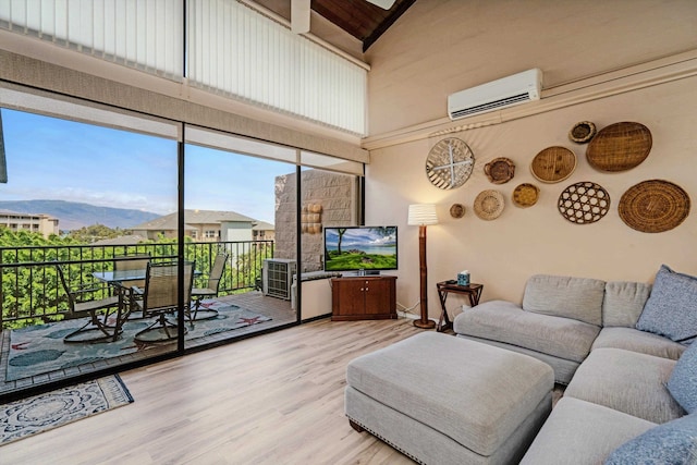 living room featuring a wall mounted air conditioner, a mountain view, a towering ceiling, and hardwood / wood-style flooring