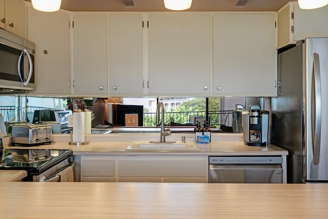 kitchen with appliances with stainless steel finishes, white cabinetry, and sink