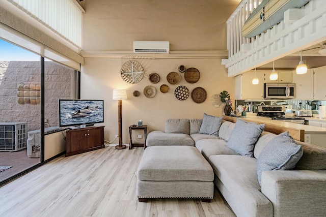 living room with a high ceiling, light wood-type flooring, and a wall unit AC