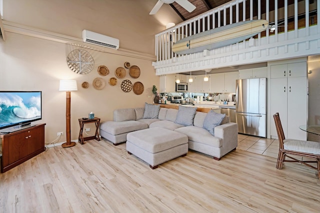 living room with an AC wall unit, ceiling fan, a towering ceiling, and light hardwood / wood-style floors