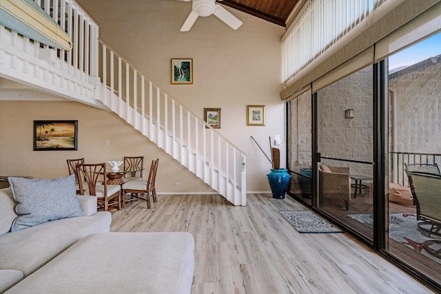 living room featuring wood ceiling, ceiling fan, light wood-type flooring, and a high ceiling