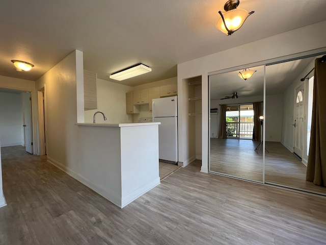 kitchen with light hardwood / wood-style flooring, kitchen peninsula, white fridge, ceiling fan, and white cabinets