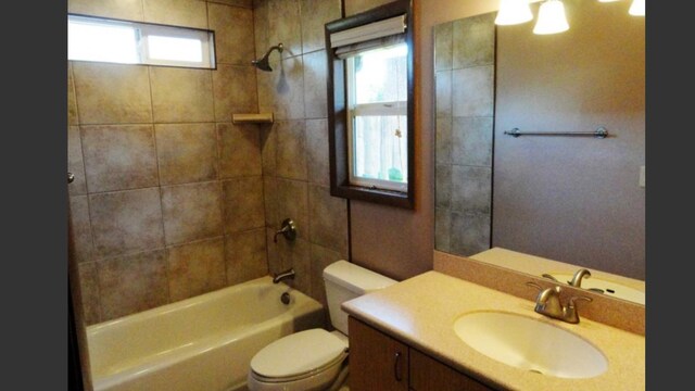 full bathroom with tiled shower / bath, vanity, and toilet