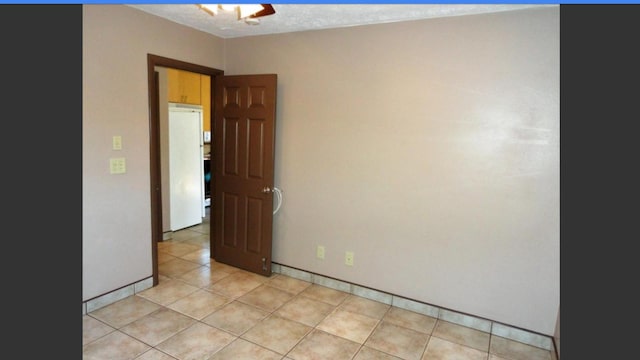 unfurnished room with light tile patterned floors and a textured ceiling