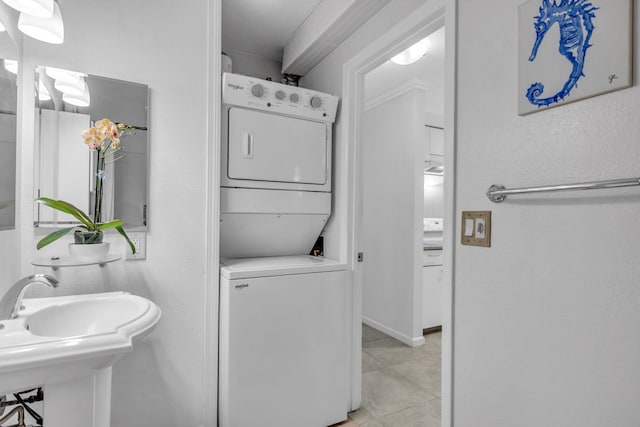 bathroom featuring stacked washer / dryer, tile patterned flooring, and a sink