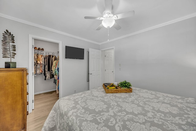 bedroom with a spacious closet, a closet, light wood-style flooring, and crown molding