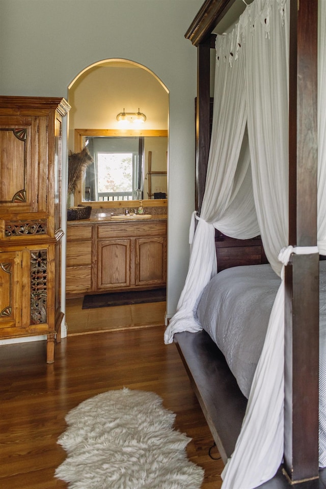 bedroom with arched walkways and dark wood-style floors