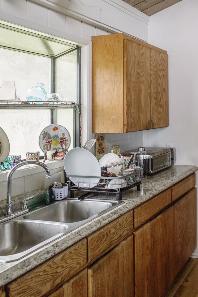 kitchen with brown cabinetry, light countertops, and a sink