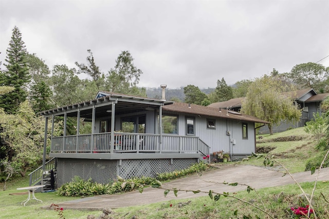 rear view of property with a wooden deck, a yard, and stairs