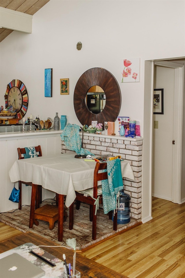 dining room with lofted ceiling with beams, baseboards, and wood finished floors