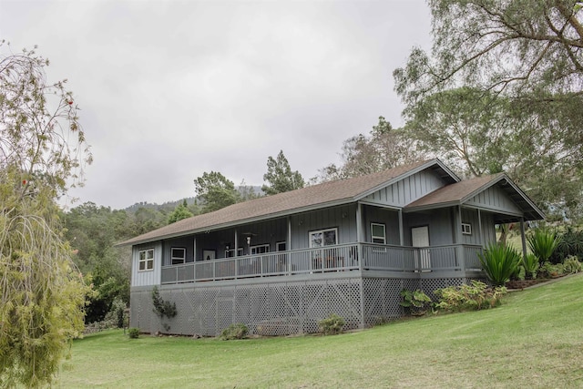 view of front facade with board and batten siding, a shingled roof, and a front yard